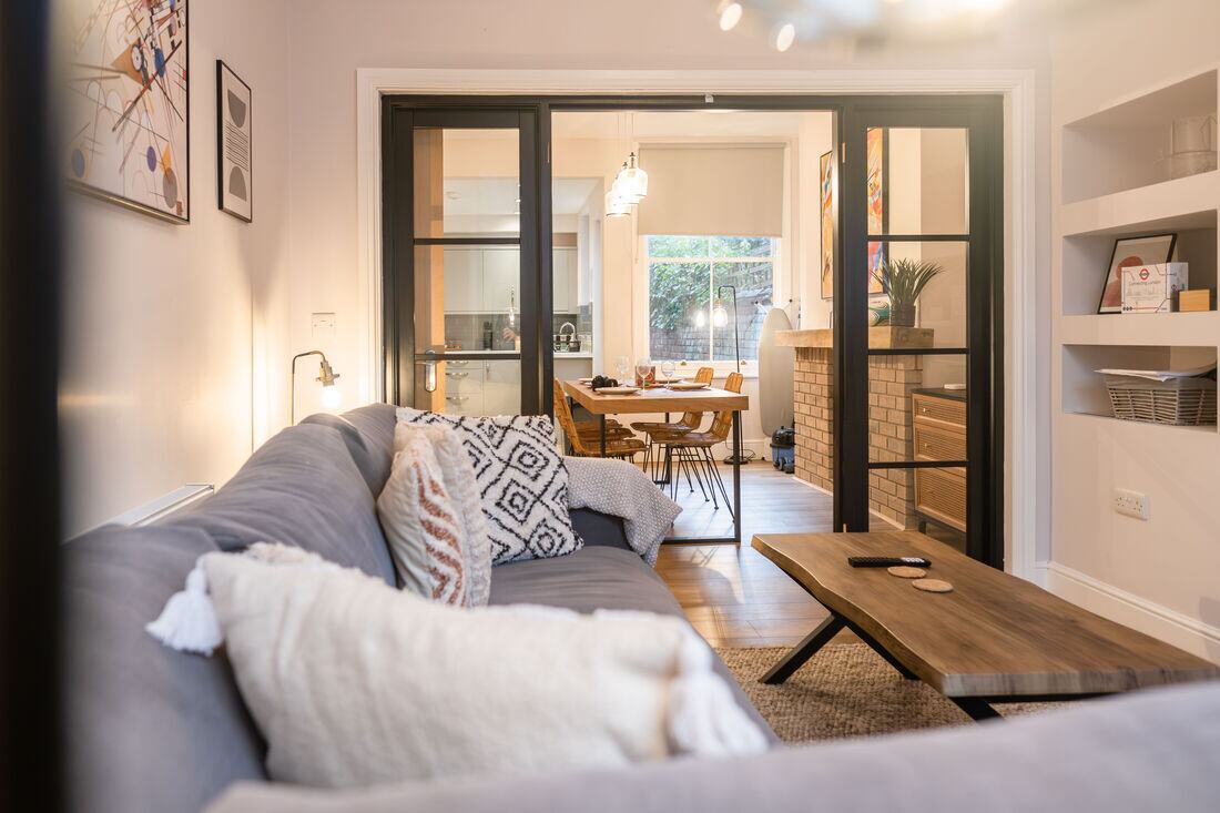 Sitting room with black Crittall-style doors opening onto a dining room.