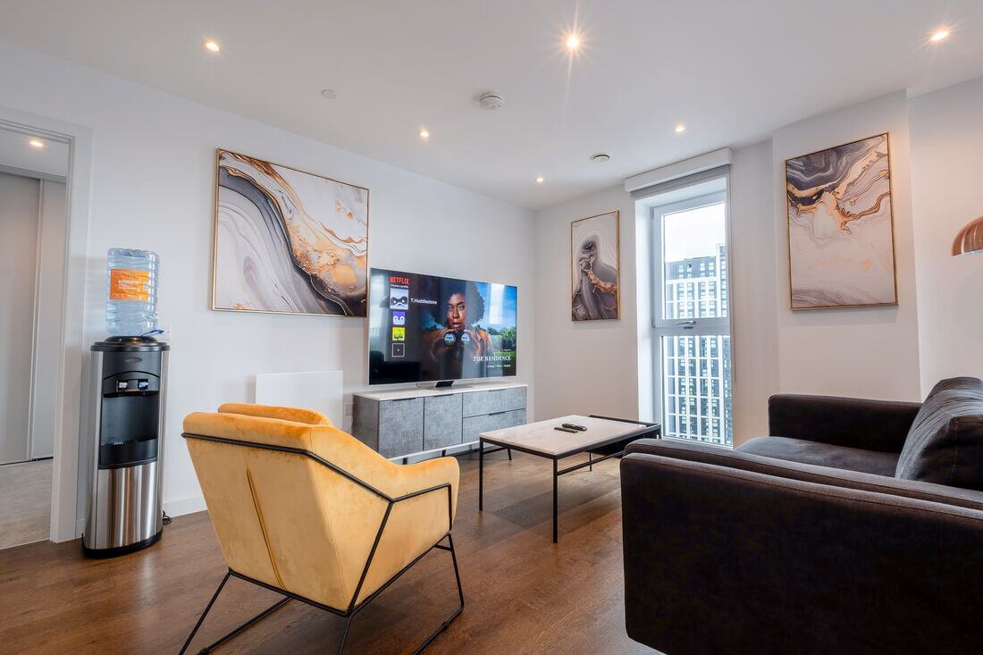 A managed apartment living room with framed prints and a velvet chair.